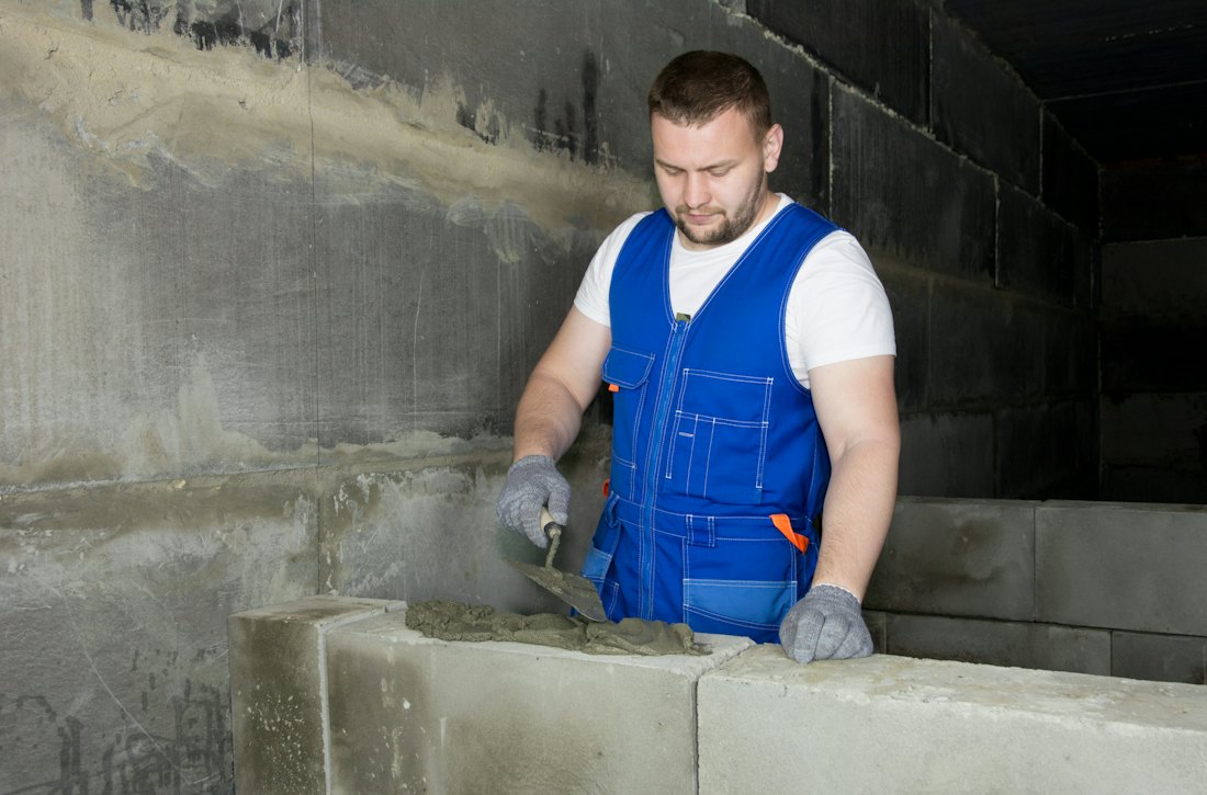 Řemeslník v montérkách při práci s betonem